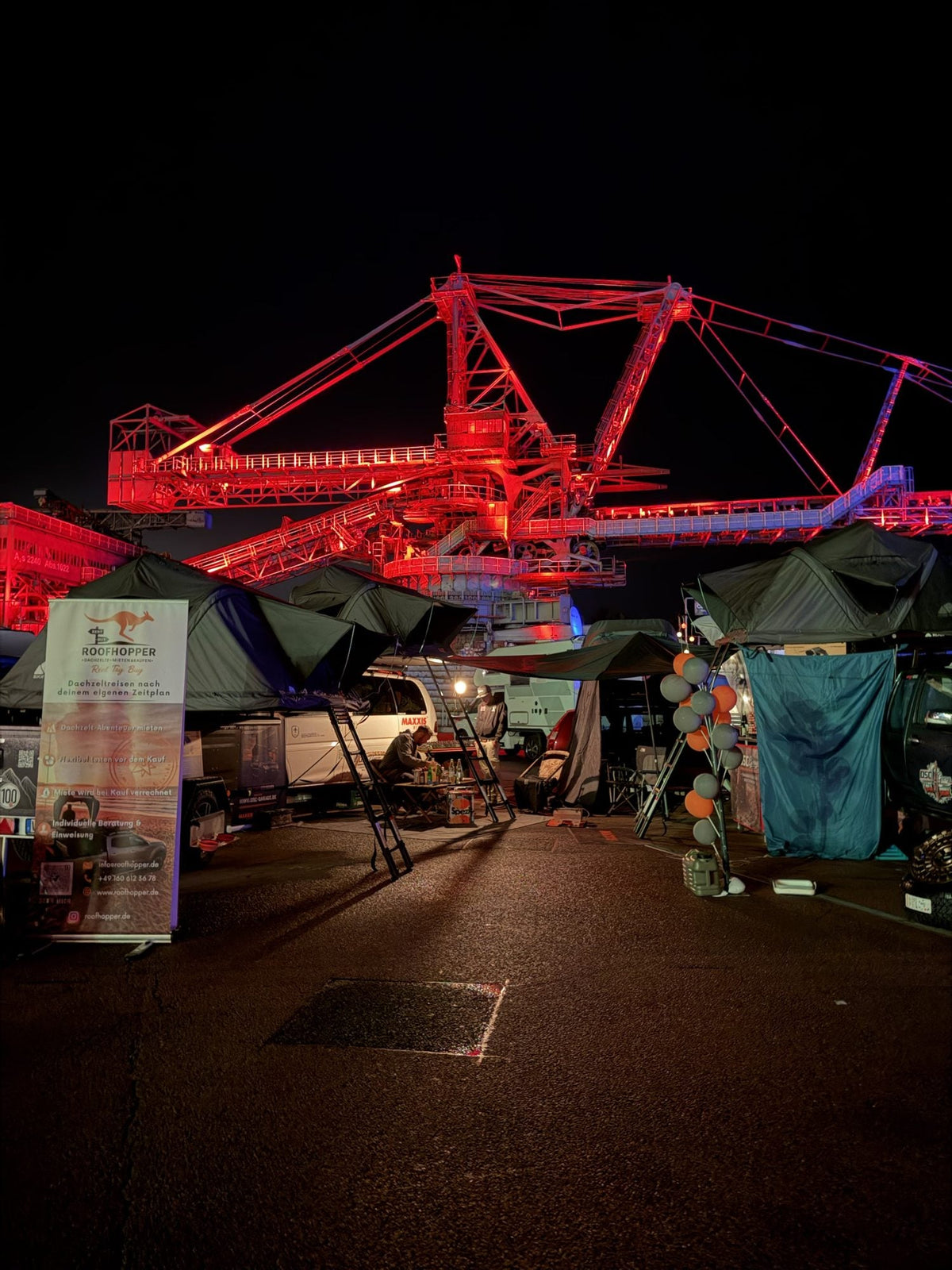 Roofhopper-Stand bei Nacht vor dem rot beleuchteten Bagger in Ferropolis