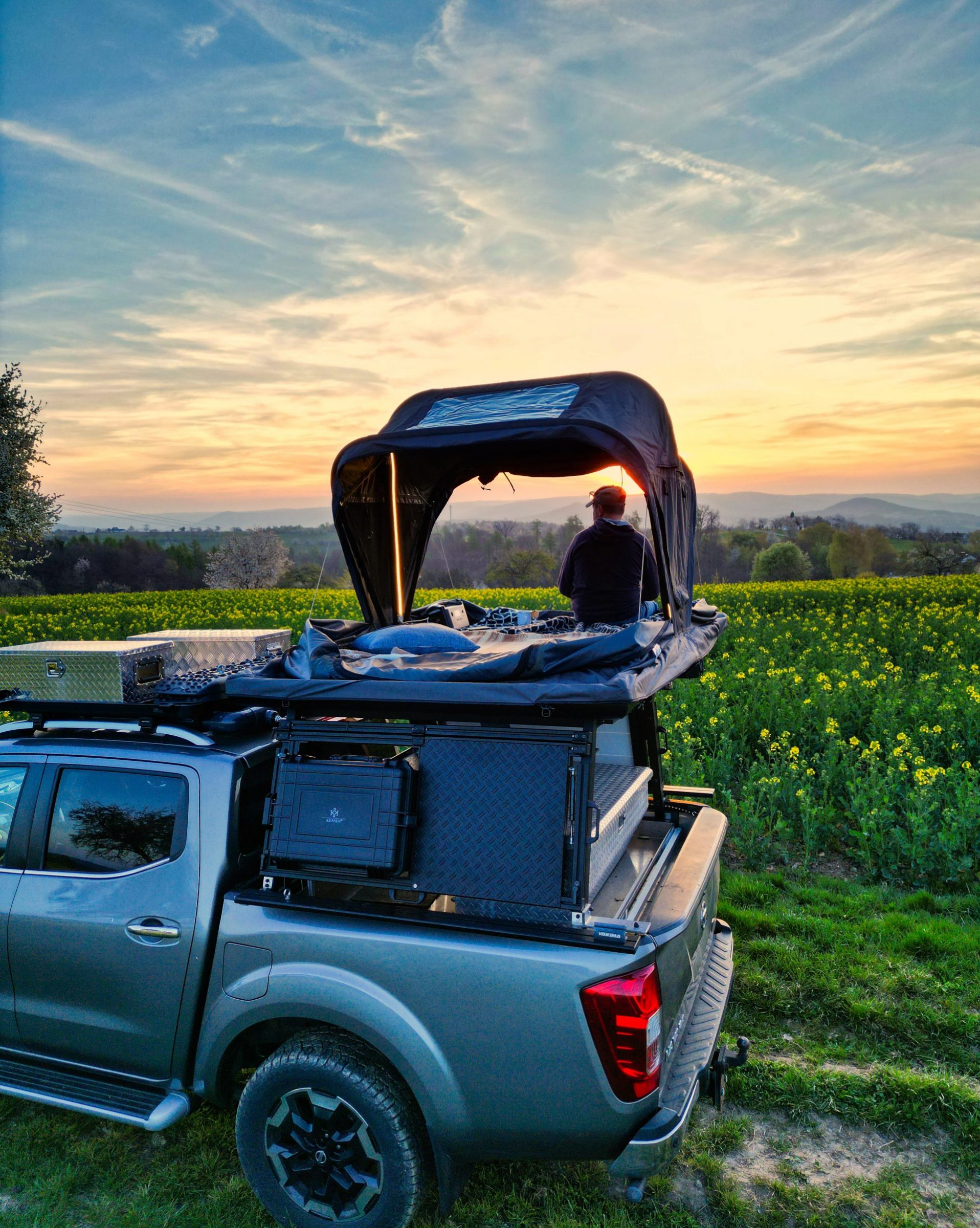 Mann im Roof Space Dachzelt beim scheine des Sonnenuntergangs. Dachzelt mieten Essen mit Roofhopper macht es möglich
